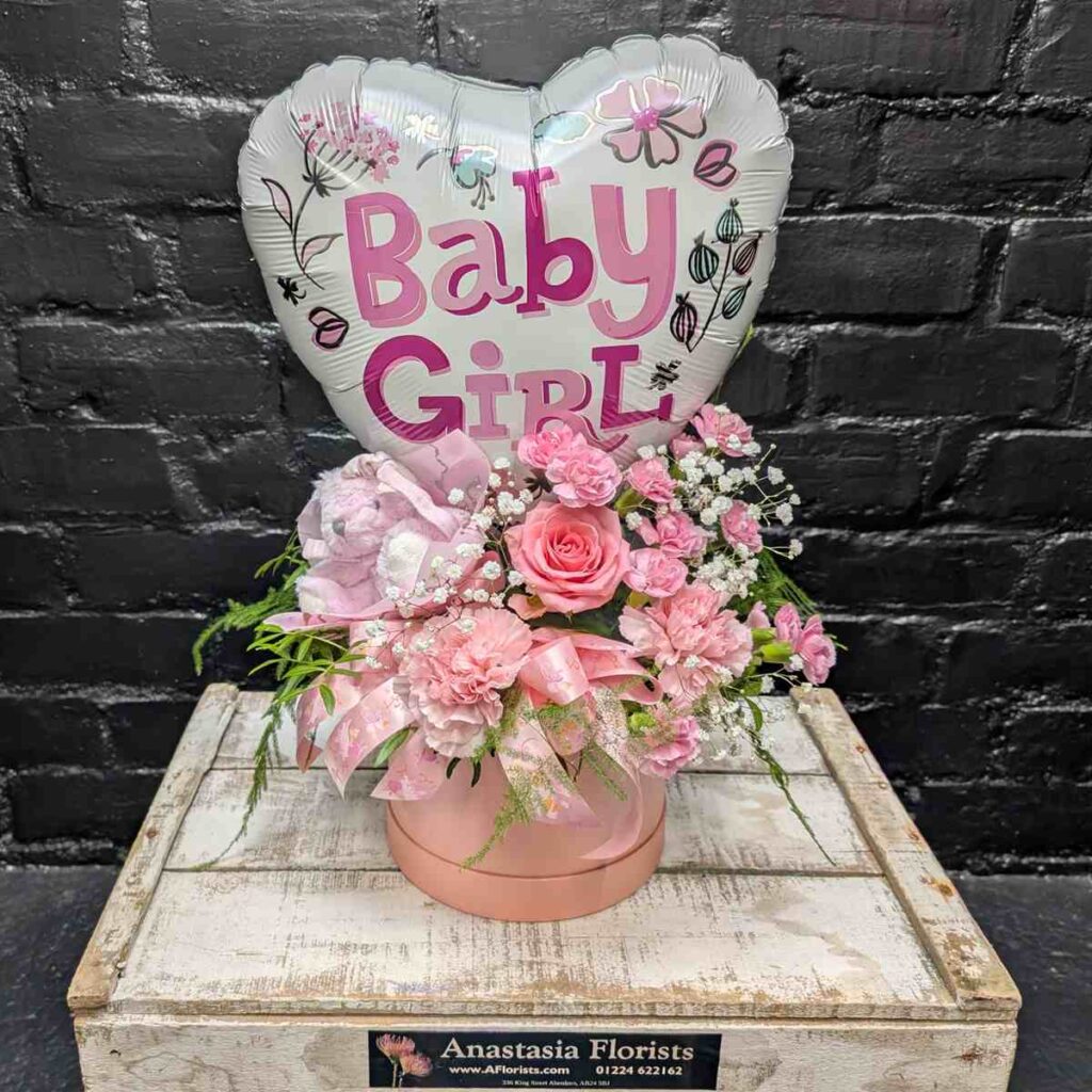 How do I make flowers last longer? “Baby Girl” new baby gift with heart balloon, pink teddy bear and pink flower arrangement in a blush hat box on a wooden crate – Anastasia Florists Aberdeen - Open View