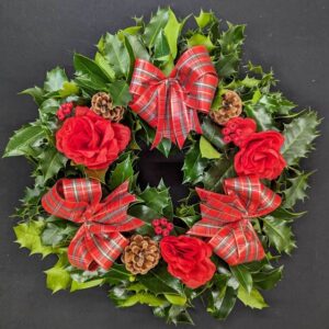 Holly graveside Christmas wreath with red tartan bows, red rose accents, pinecones and red berries