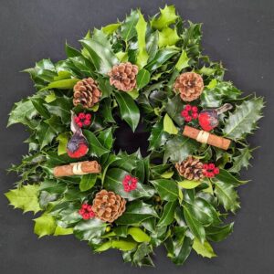 Holly graveside Christmas wreath with robin decorations, pinecones, red berries and cinnamon
