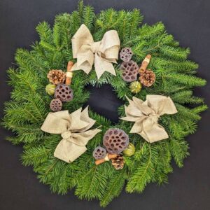 Pine Christmas door wreath with neutral linen-style bows, pinecones, lotus pods and cinnamon