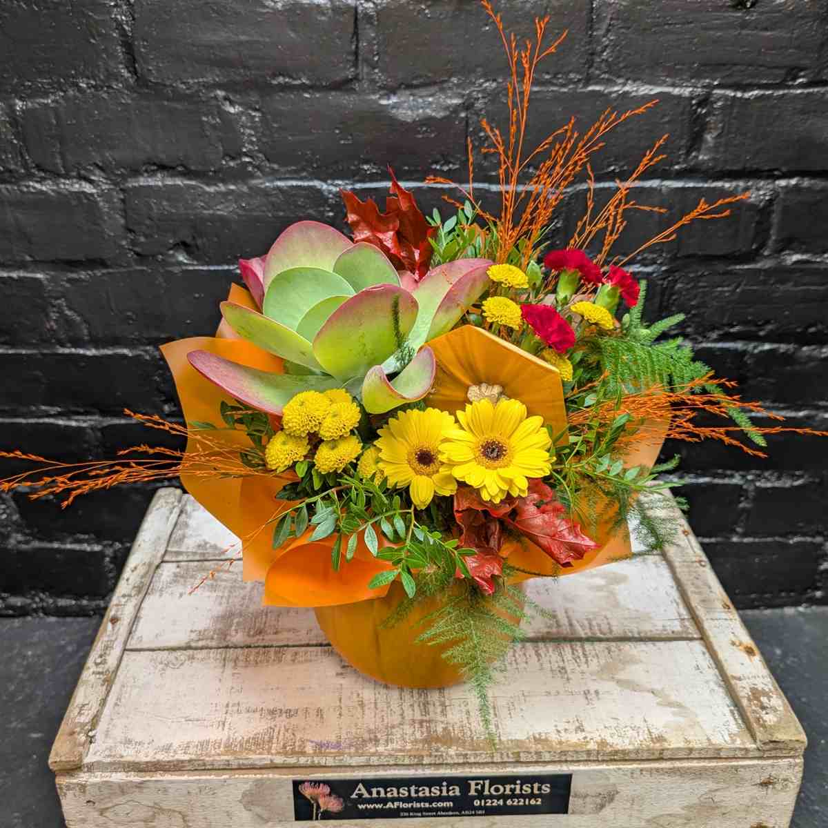 Bring the warmth of autumn into your home with this unique Pumpkin Delight arrangement. Artfully arranged inside a real pumpkin container, featuring vibrant gerberas and chrysanthemums. Available for Same-Day Delivery in Aberdeen - Side View