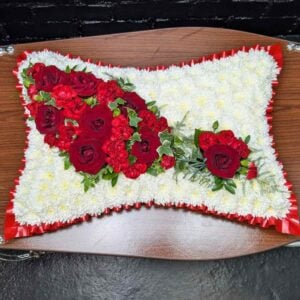 Red rose funeral pillow tribute with white chrysanthemum base and red ribbon edge