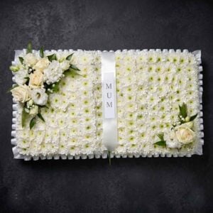 White rose funeral book tribute with massed chrysanthemum base and central white ribbon