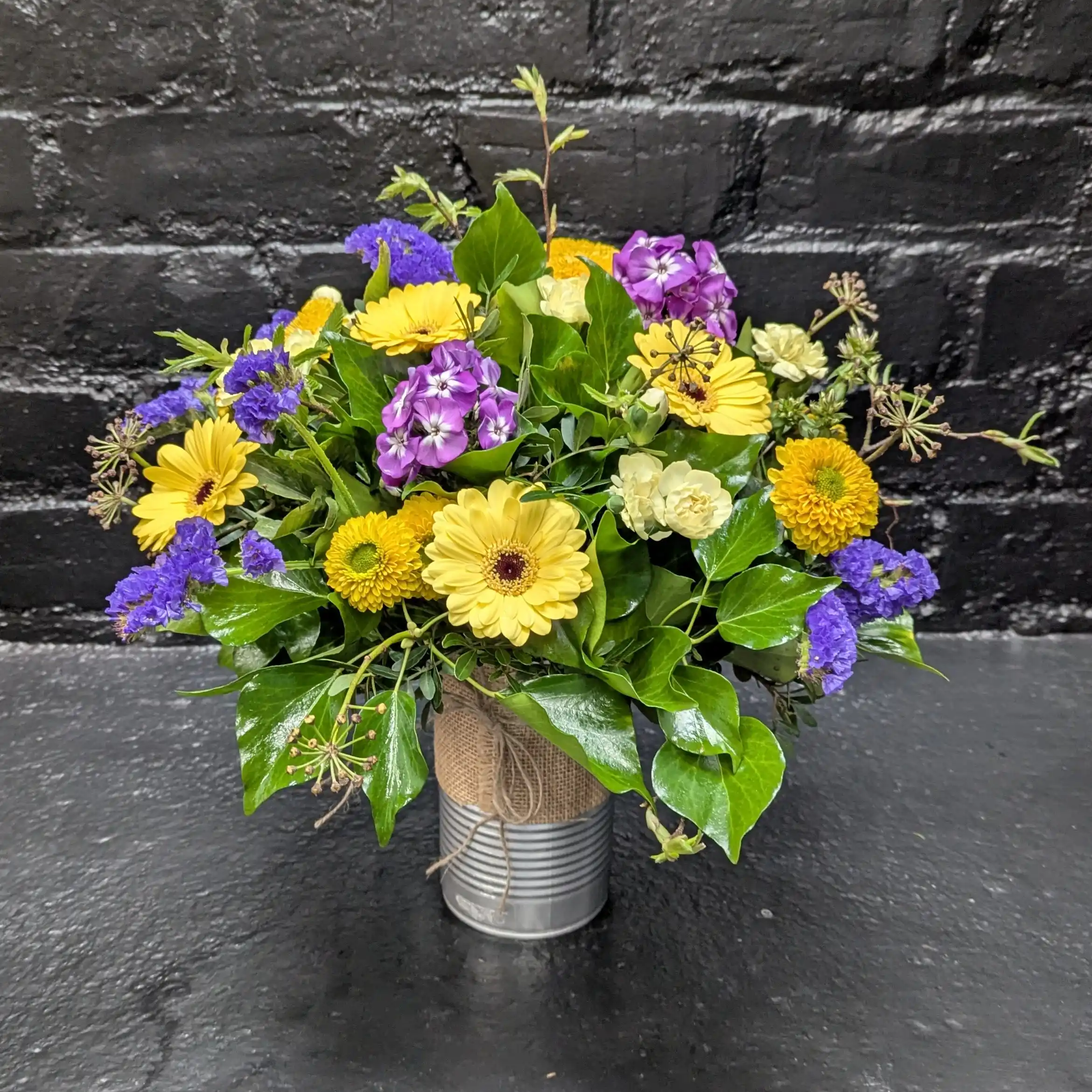 Colourful arrangement of seasonal flowers in a tin – angle view