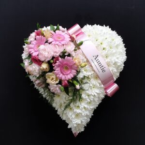 White chrysanthemum heart funeral tribute with pink flowers and Auntie ribbon on a black background
