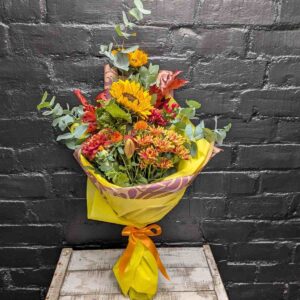 Autumn Glow hand-tied bouquet with sunflowers, orange chrysanthemums, berries and eucalyptus in bright yellow wrap with orange ribbon – Anastasia Florists Aberdeen