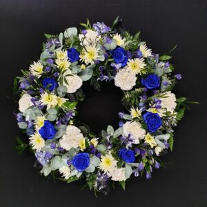Blue and white funeral wreath with blue roses, white carnations and eucalyptus