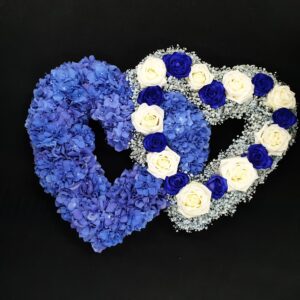 Blue and white double heart funeral tribute with blue hydrangea, gypsophila and blue and white roses on a black background