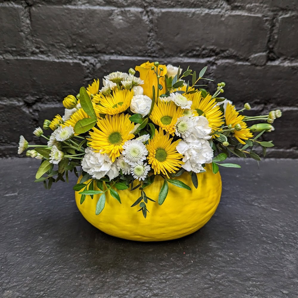 Vibrant yellow and white floral arrangement in a yellow Melon