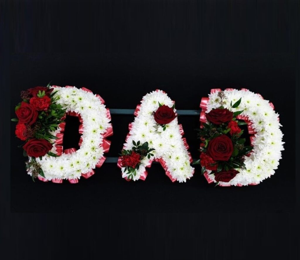 What Flower Arrangements are Suitable for a Male Funeral? DAD funeral letter tribute with white chrysanthemums, pink ribbon edging and deep red roses