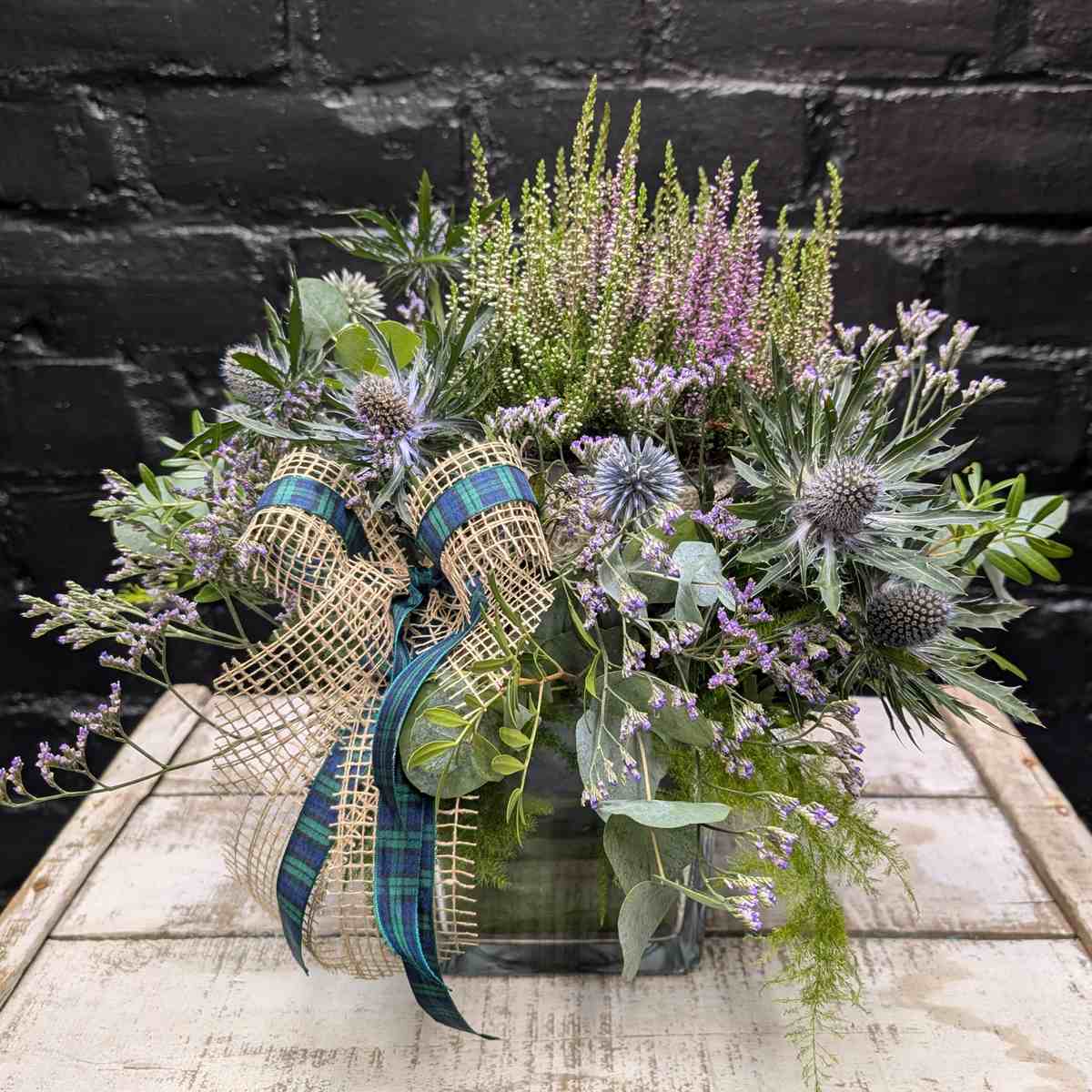 Scottish thistle and heather flower arrangement with lilac blooms, foliage and tartan ribbon in a glass cube vase – Anastasia Florists Aberdeen