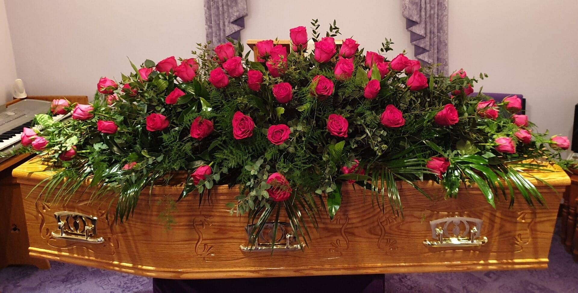 Full-length red rose coffin spray on wooden coffin
