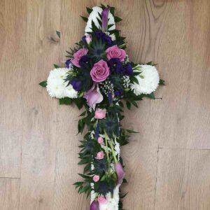 Lilac and purple funeral cross with white chrysanthemum base, roses, calla lilies and thistles