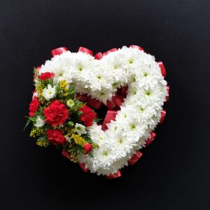 Heart-shaped floral tribute with white chrysanthemums and red accents