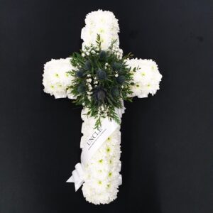 White flower cross funeral tribute with greenery