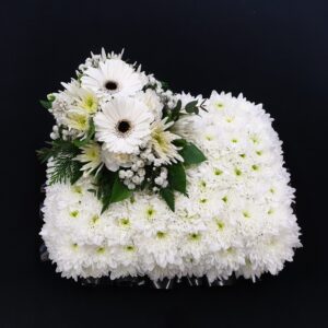 Miniature white chrysanthemum funeral pillow with white gerbera and gypsophila on a black background