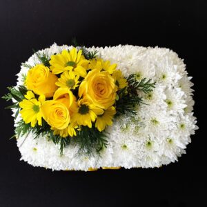 Miniature white chrysanthemum funeral pillow with yellow roses and daisy flowers on a black background