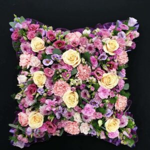 Pastel funeral cushion tribute with cream roses, pink carnations and lilac flowers