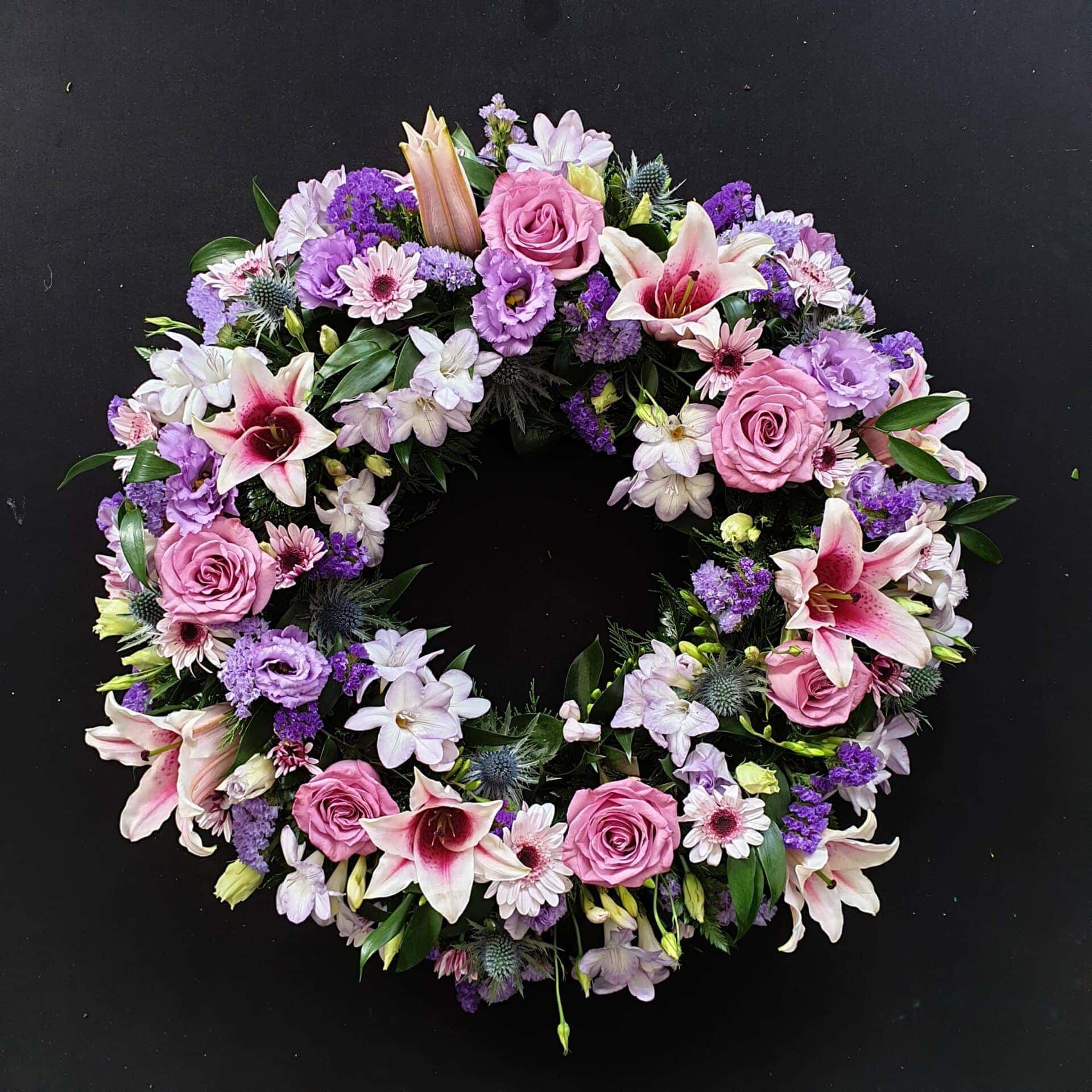 Pink and purple funeral wreath with lilies and roses