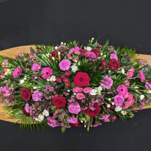 Red and pink coffin spray with roses, gerberas and carnations on wooden coffin