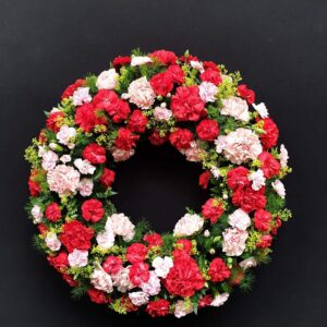 Red and pink carnation funeral wreath with greenery
