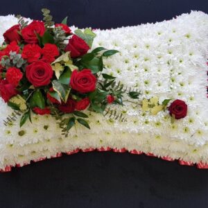 Red rose funeral pillow tribute with white chrysanthemum base and red ribbon edge