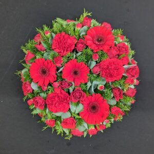 Red funeral posy with gerberas, roses, and greenery