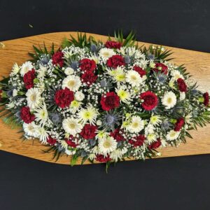 Red, white and blue coffin spray with carnations, gerberas, chrysanthemums and thistles on wooden coffin