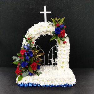 Red, white and blue Gates of Heaven funeral tribute with white chrysanthemums, white cross, open gates and red and blue rose sprays.