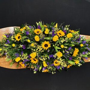 Yellow and purple sunflower coffin spray on wooden coffin