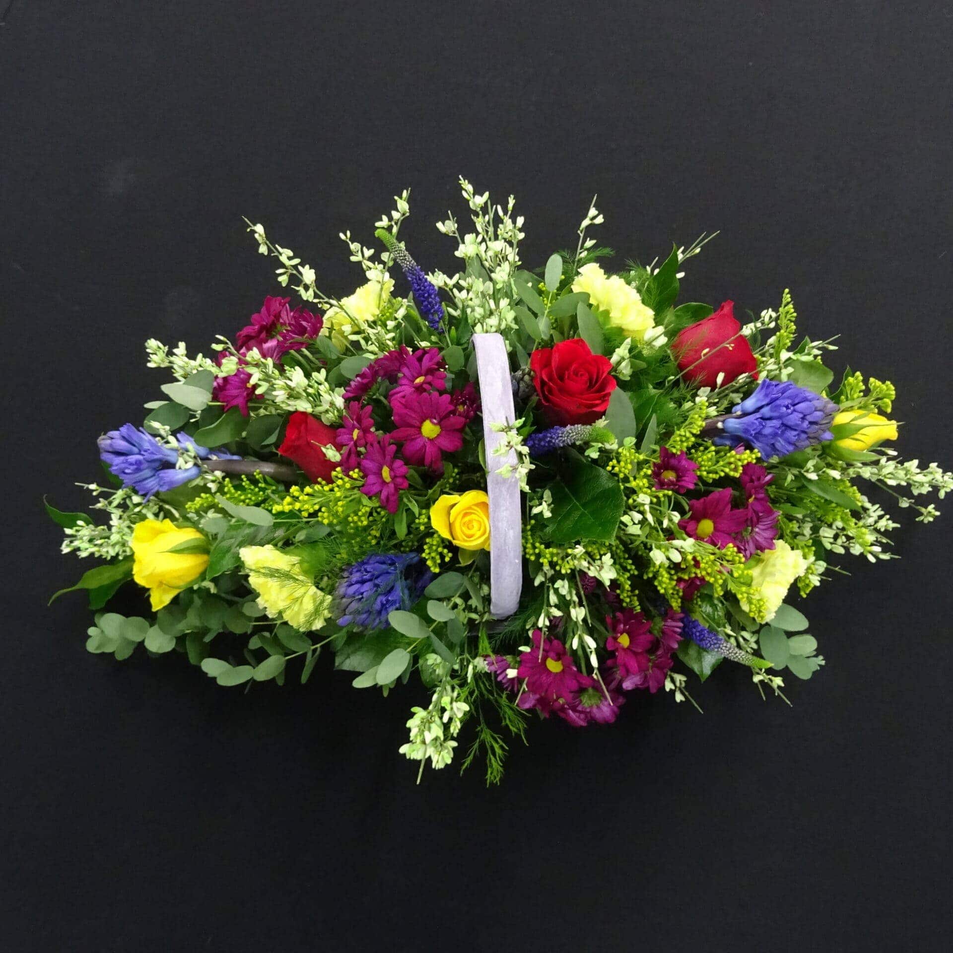 Vibrant mixed funeral flower basket with red, yellow and purple flowers in a handled basket from Anastasia Florists Aberdeen.