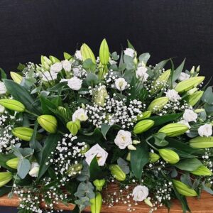 White lily and rose coffin spray with gypsophila on wooden coffin