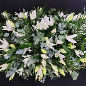 White lily coffin spray with eucalyptus on wooden coffin