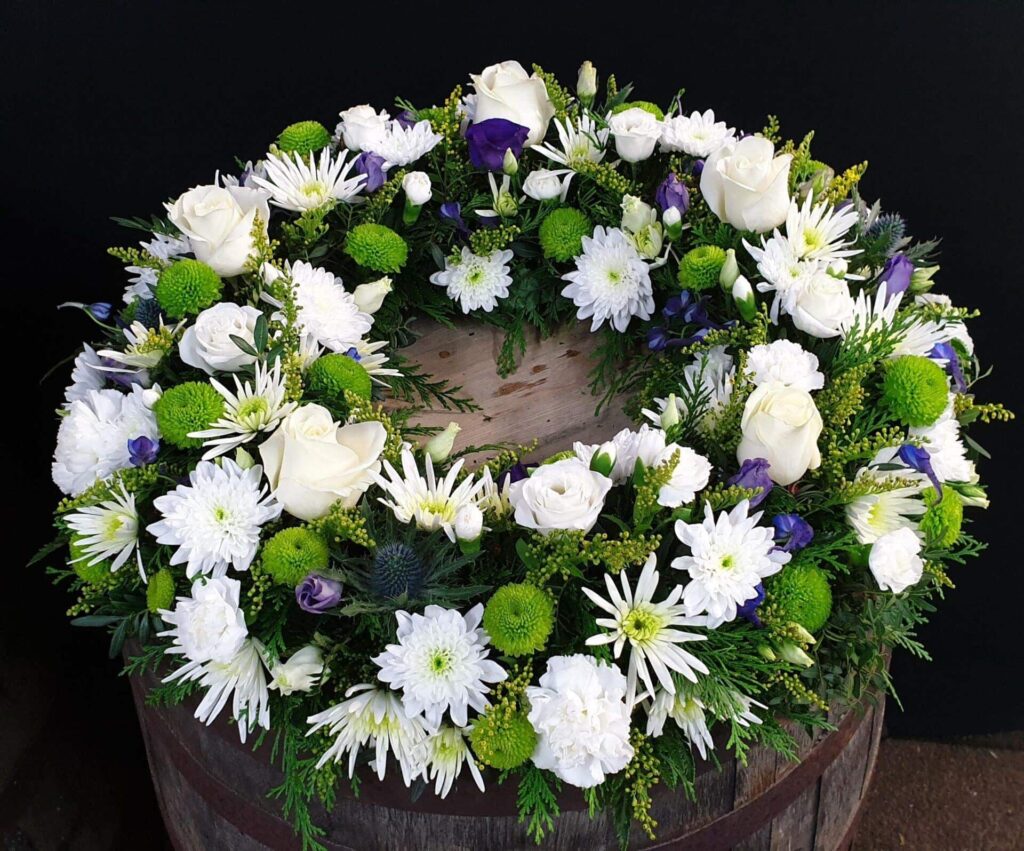 What Flower Arrangements are Suitable for a Male Funeral? White rose and Purple Statice funeral wreath tribute