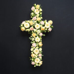 Soft yellow and peach flower funeral cross on black background