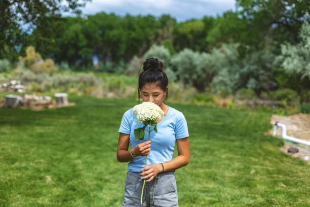 A woman smelling flowers outside in a garden in Scotland