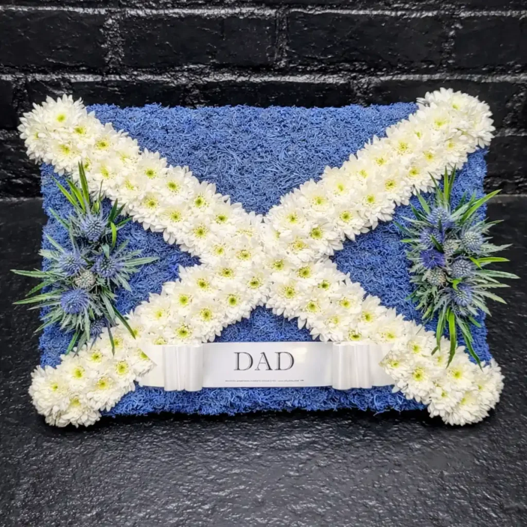 Funeral Flower Tributes Explained: Coffin Sprays, Wreaths, Hearts, Posies & More Dad Scottish flag funeral tribute in blue and white with white chrysanthemum cross