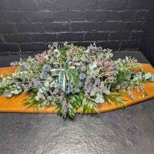 Hills of Scotland double-ended casket spray featuring blue thistles, pink heather, eucalyptus, and a green tartan ribbon by Anastasia Florists Aberdeen.