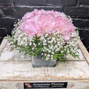 Pink peony and gypsophila glass cube arrangement by Anastasia Florists.