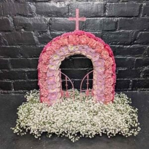 Pink Gates of Heaven funeral tribute with an arch of pink carnations and chrysanthemums, opening gates, a cross and a bed of gypsophila