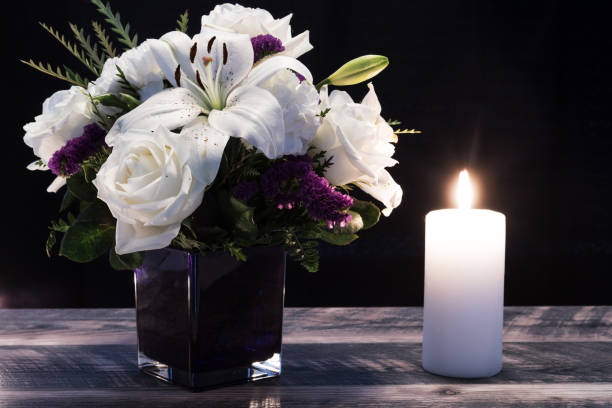 A sympathy flower in a vase beside a lighted candle