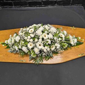 White flower funeral coffin spray arranged on wooden coffin