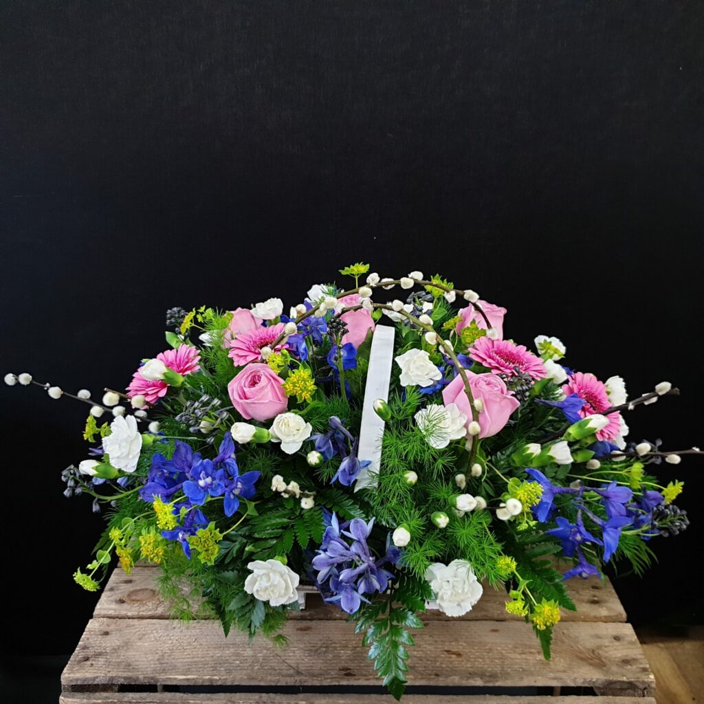 A funeral flower basket on top of a coffin