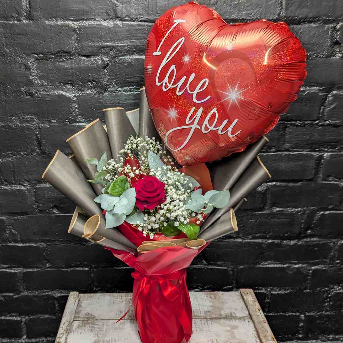 Heartfelt Message Arrangement 1 Single red rose arrangement with white Gypsophila, eucalyptus, and a large heart-shaped 'I Love You' balloon