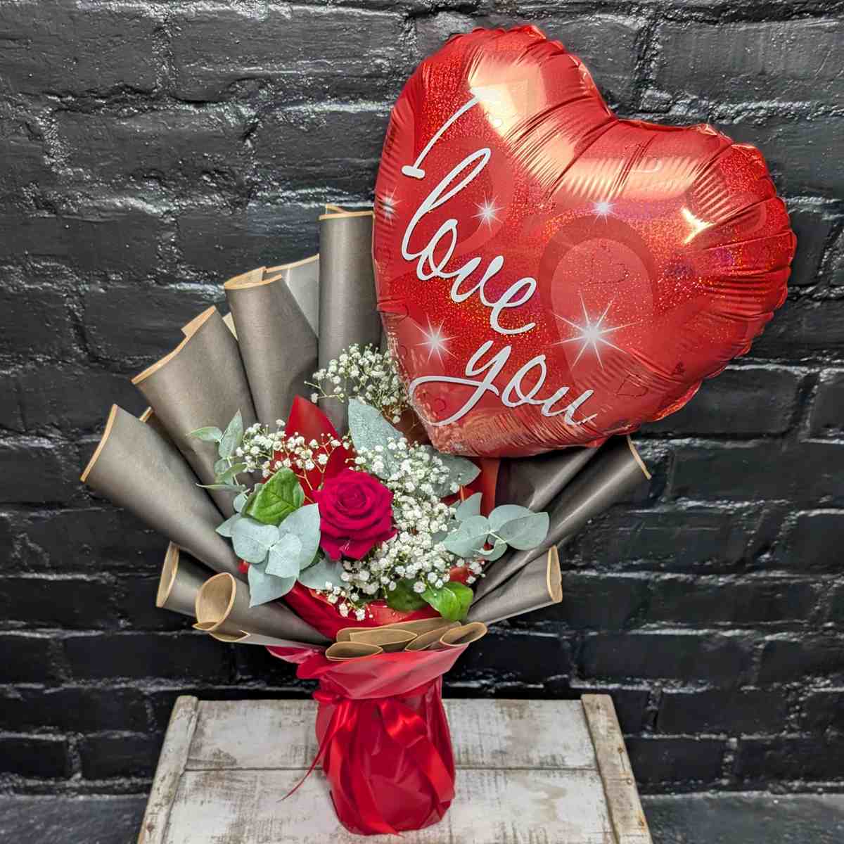 Heartfelt Message Arrangement 2 Single red rose arrangement with white Gypsophila, eucalyptus, and a large heart-shaped 'I Love You' balloon
