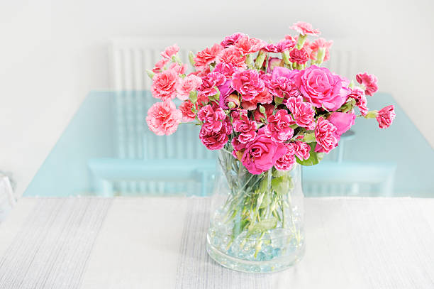 Carnations in glass dining table with radiator and room interior background