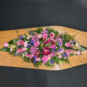 Luxury full-length Casket Spray with pink Stargazer lilies, pink roses, carnations, and purple statice, available in 3 to 5-foot sizes.
