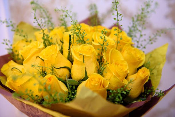 A bouquet of yellow roses with long green leaves
